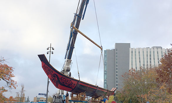 crane and rigging moving large canoe